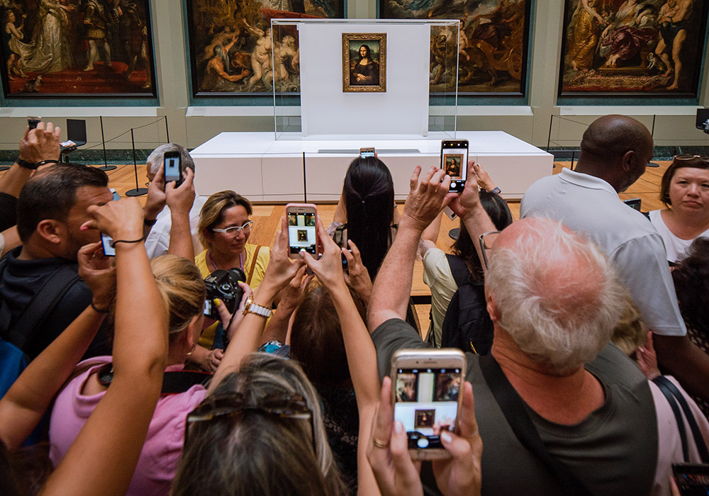 People in a crowd using cellphones to take pictures of the Mona Lisa