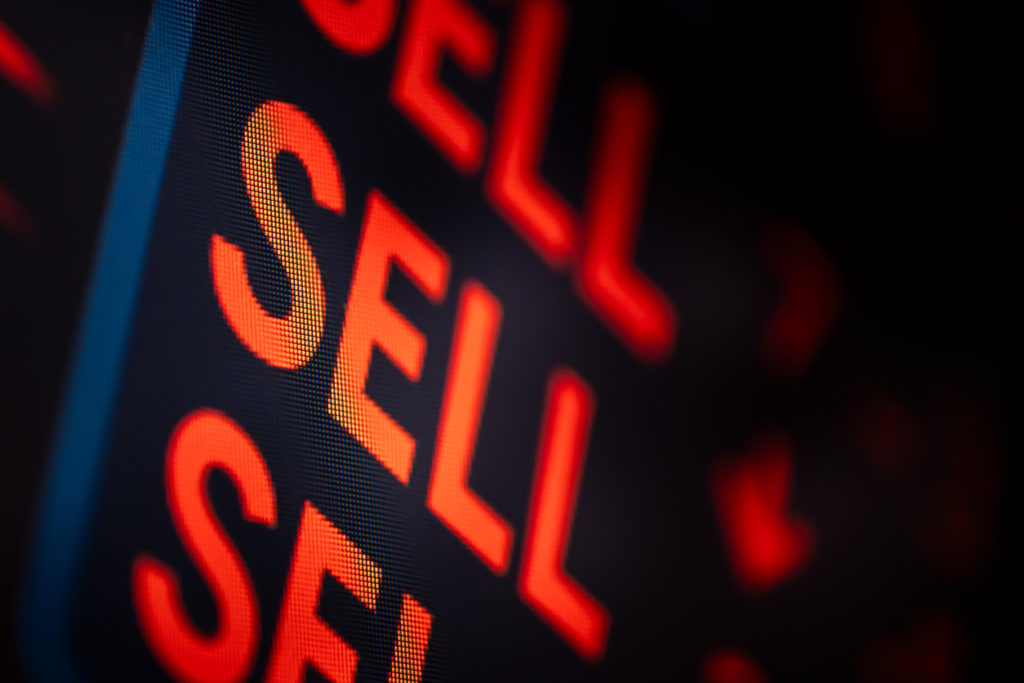 Close-up of a trading screen showing multiple red "SELL" alerts, indicating a stock market drop or panic selling event. Photograph of computer screen.